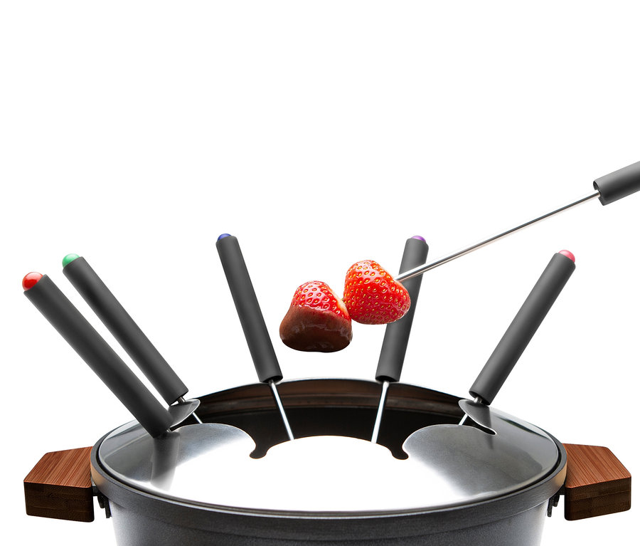 Zwei Erdbeeren auf Gabeln über einem Fondue.