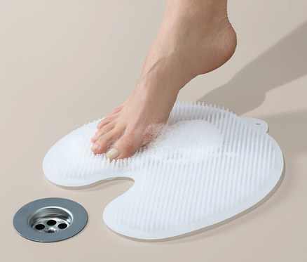 Ein Fuß steht auf der Fuß-Reinigungs-und-Massage-Matte, der andere Fuß ist daneben.