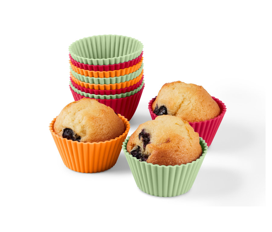 Ein Stapel aus 12 Muffinförmchen und drei Muffins in orangefarbenen, pinken und grünen Förmchen.
