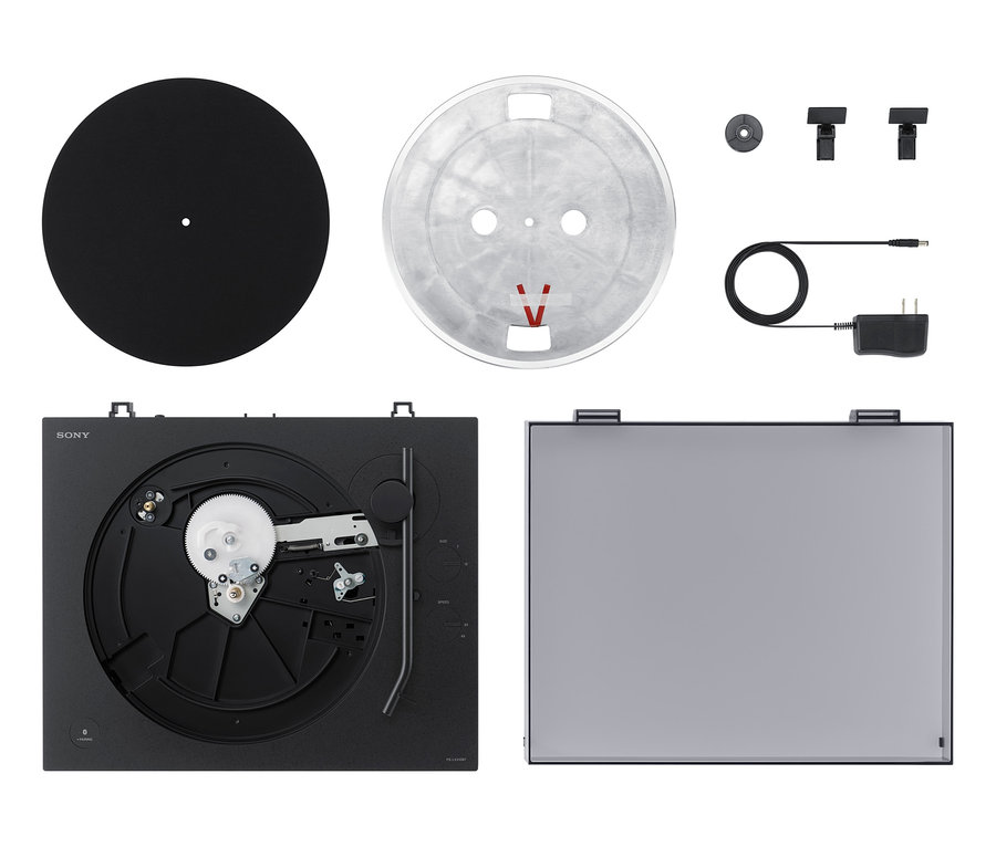 Ein schwarzer Sony-Plattenspieler »PS-LX310BT«, eine Schallplatte und Zubehör auf einem weißen Hintergrund ausgebreitet.