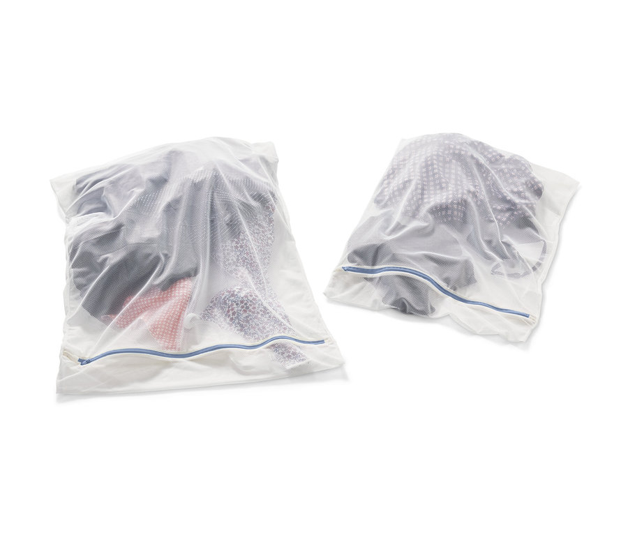 Zwei weiße XL-Wäschenetze, gefüllt mit Kleidung.