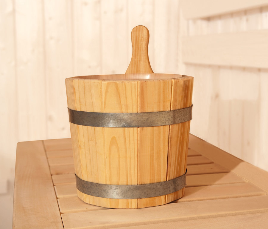 Ein Holz-Eimer mit Schöpfkelle aus dem WEKA-Aufguss-Set steht auf einer Holzbank in einer Sauna.