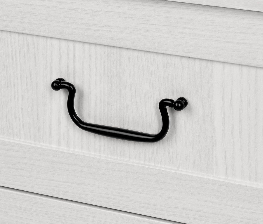 Detailaufnahme einer Kommode mit Tür und Schubladen, mit einem schwarzen Griff.