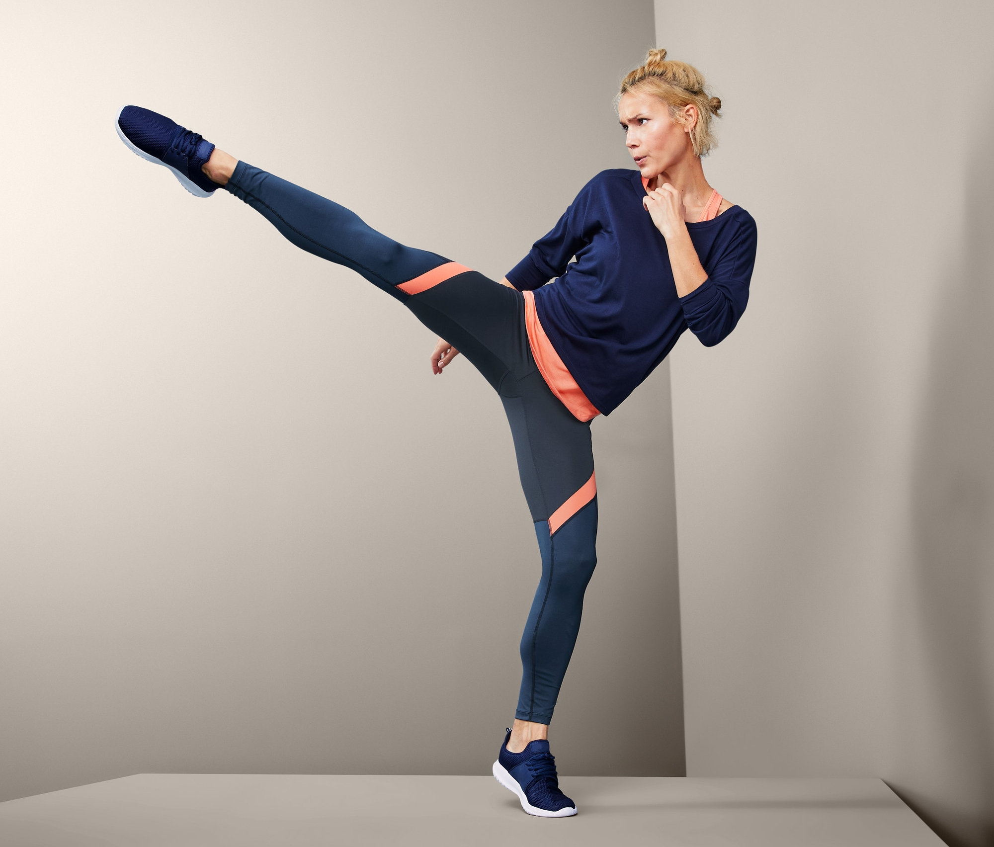 Frau macht einen Kick in Colorblocking-Sporttight.
