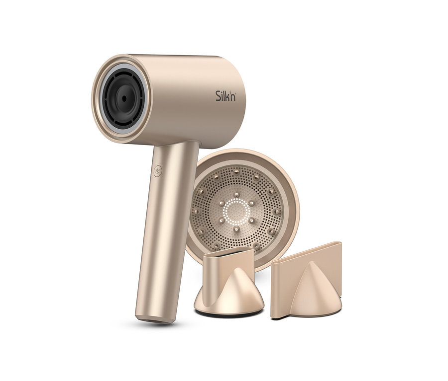 Goldener Silk'n Haartrockner »SilkyAir Pro« und zwei Aufsätze liegen auf einem weißen Hintergrund.