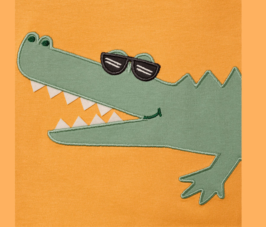 Gelbes T-Shirt mit einer Applikation eines grünen Krokodils mit Sonnenbrille.