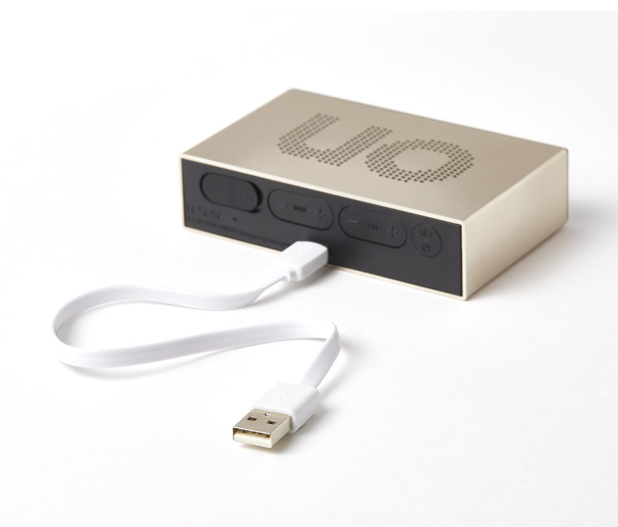 Champagnerfarbener Lexon »FLIP PREMIUM« Wecker mit Ladekabel auf weißem Hintergrund.