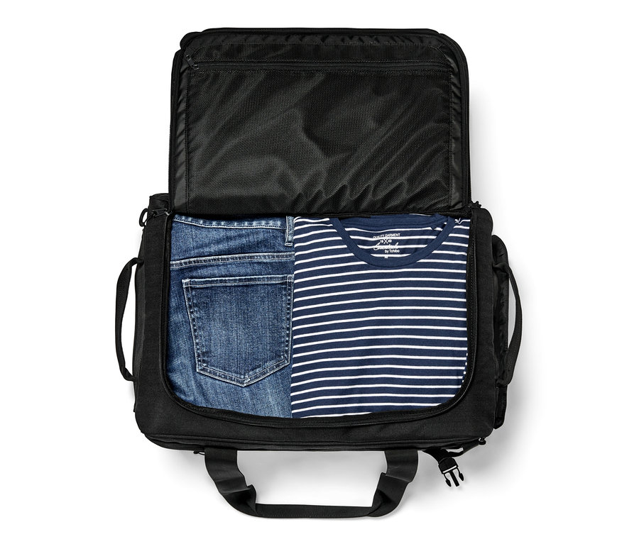 Geöffnete schwarze Duffle-Bag mit Jeans und einem gestreiften T-Shirt darin.