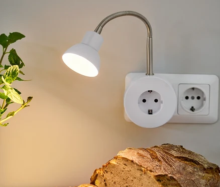 Beleuchtete LED-Schwenkleuchte über Brot und Teller mit Aufstrich.