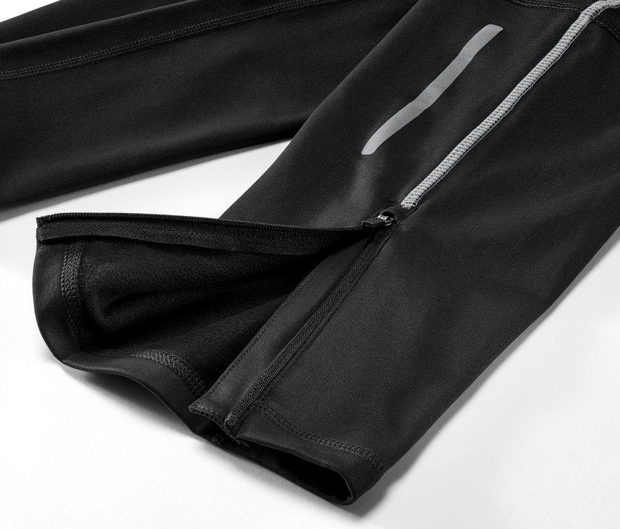 Detailaufnahme einer schwarzen Thermo-Lauftight mit geöffnetem Reißverschluss am Bein.