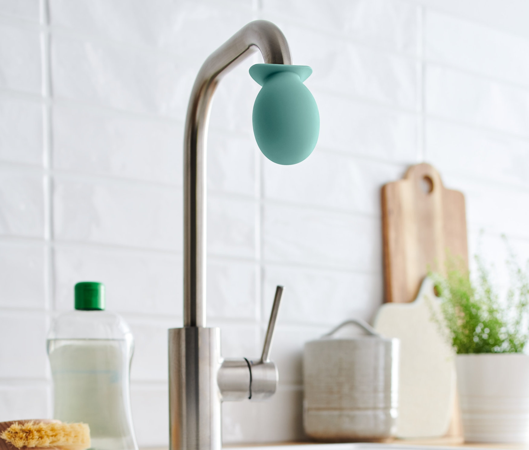 Auf einem Wasserhahn befindet sich ein grüner Wasserhahn-Entkalker-Aufsatz.