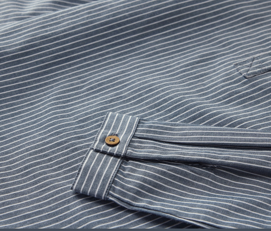 Detailansicht eines Kinderhemds mit Streifen und Knopf.