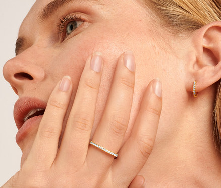 Nahaufnahme einer blonden Frau mit 585 Gold Ring Eternity Zirkonia und 585 Gold Creolen Zirkonia.