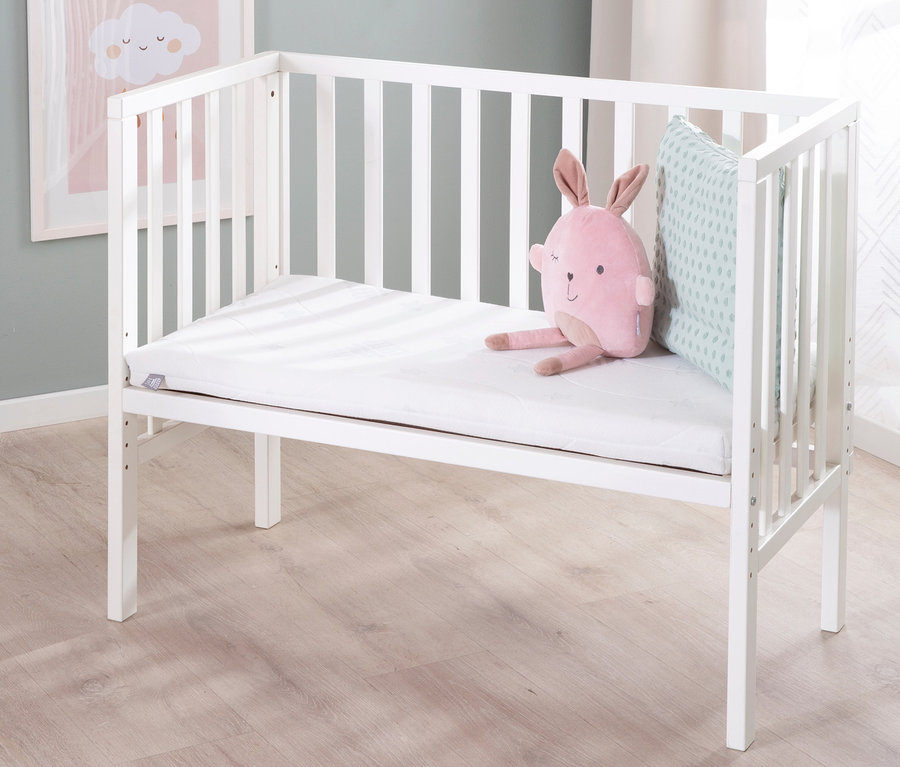 Weißes roba 2-in-1-Beistellbett »safe asleep®« mit rosa Häschen und Kissen.