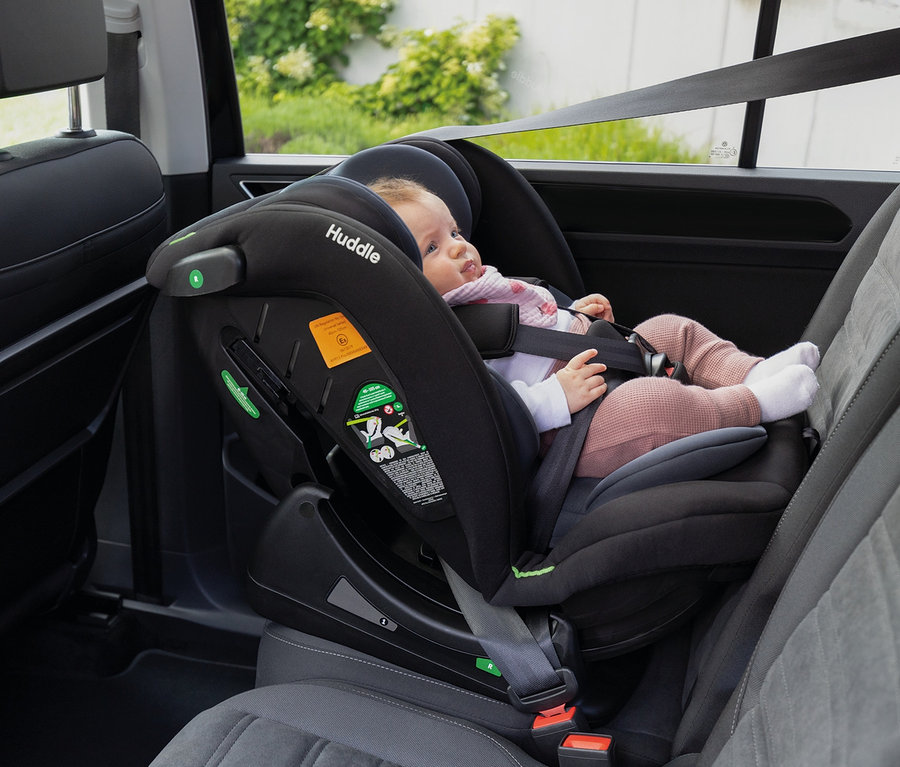 Ein Baby sitzt in einem schwarzen Osann Kindersitz »Huddle 2« im Auto.
