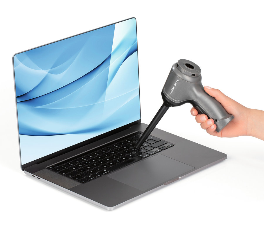 Eine Hand verwendet einen grauen Akku-Handstaubsauger, um eine Laptop-Tastatur zu reinigen.