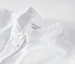 Detailansicht einer weißen Bluse mit Rüschendetail.