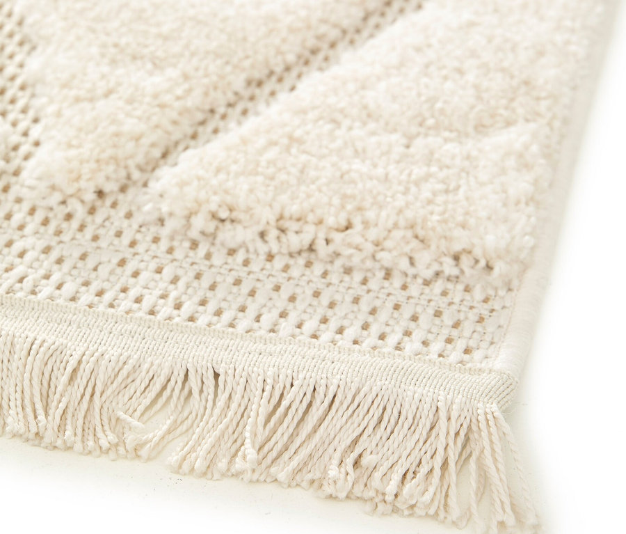 Detailansicht eines beigen NATIVO Boho Lines Teppichs mit geometrischem Muster und Fransen.