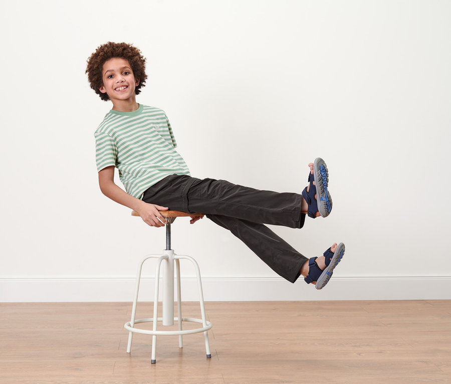 Junge sitzt auf einem Hocker und trägt eine Kinder-Funktionshose.