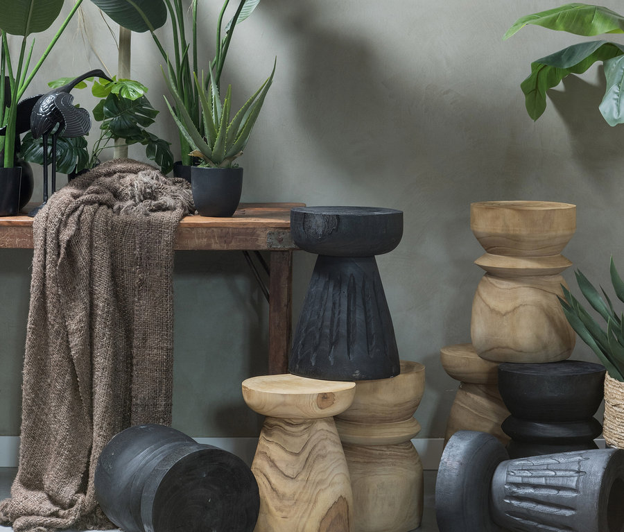 Verschiedene Woood Bikkel Hocker aus Holz in Natur- und Schwarzfarben. Einige sind übereinander gestapelt.