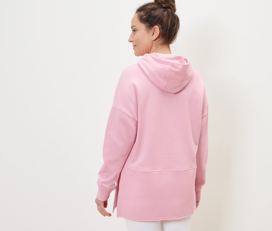 Frau trägt langes Kapuzensweatshirt, rosa.