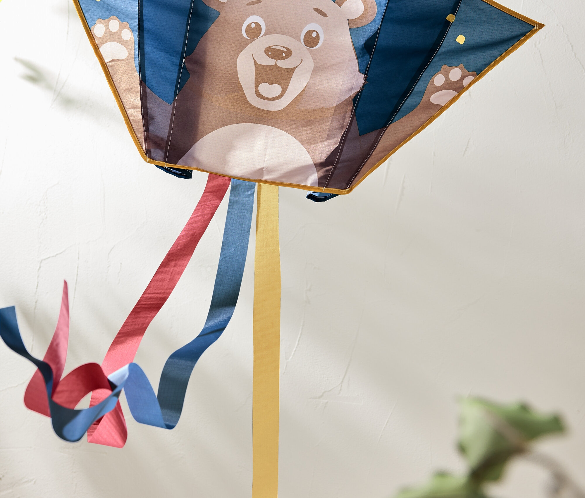 Drachen mit Bärenbild und bunten Bändern, die dahinter wehen.