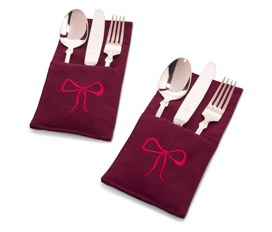 Zwei Bestecksets in weinroten Stoffhüllen mit roter Schleifenstickerei.