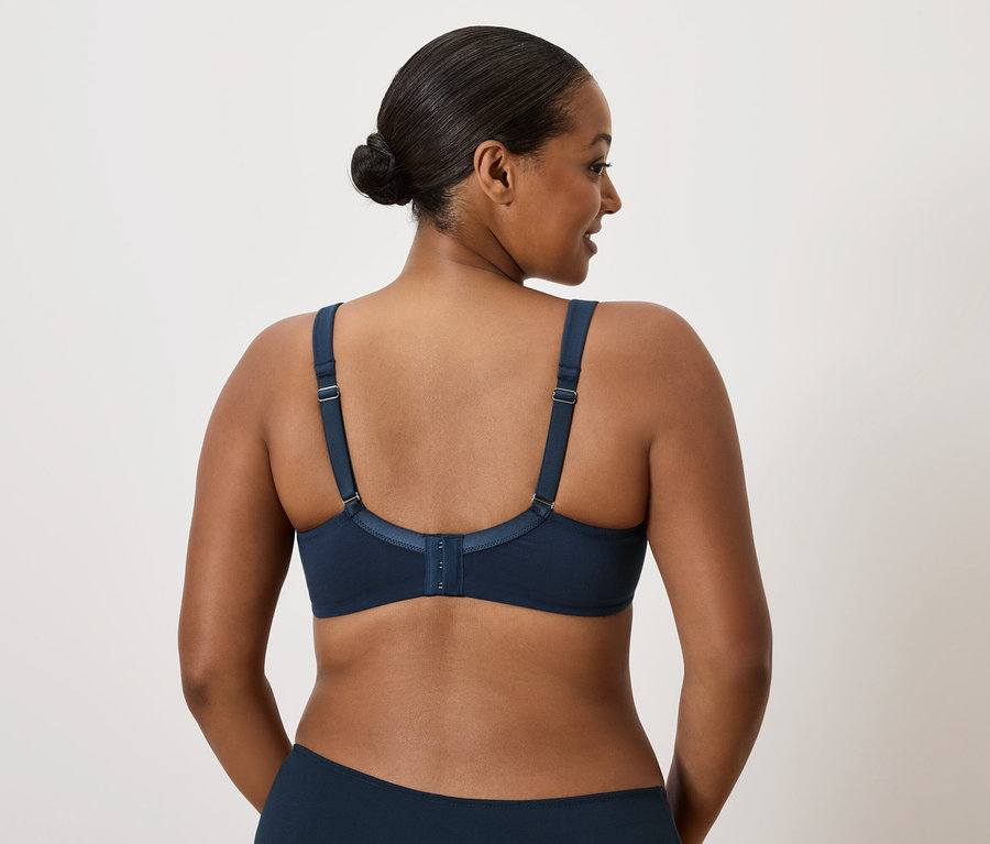 Frau mit dunklen Haaren trägt einen dunkelblauen BH.