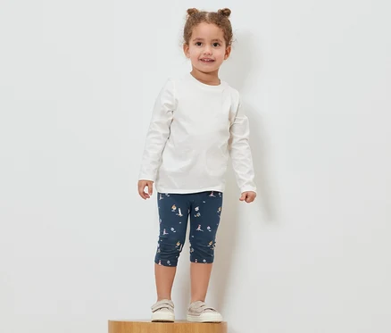 Mädchen steht auf einem Holzsockel und trägt eine maritime 3/4-Leggings.