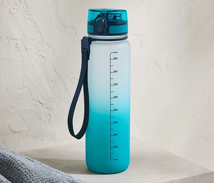 Eine blaue Trinkflasche mit Farbverlauf steht auf einem Betonsims.