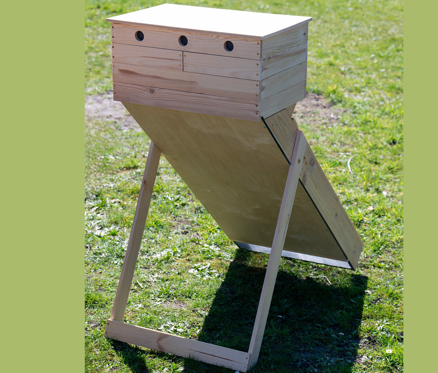 Solar-Dörrschrank aus Holz auf einer Wiese.