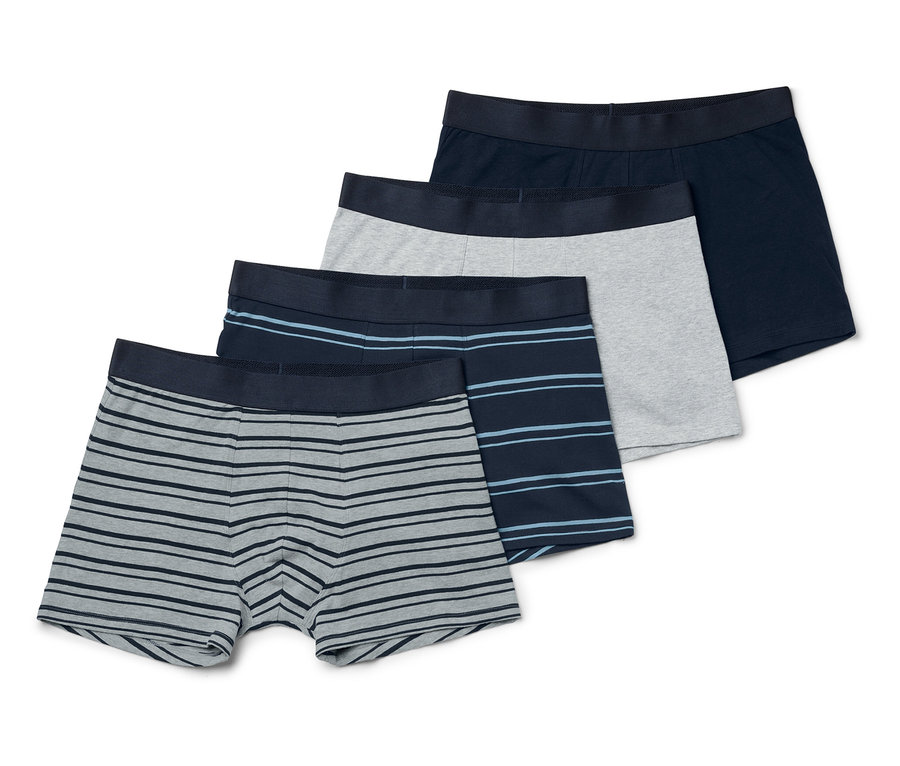 Vier Herren Boxershorts liegen übereinander. Eine ist dunkelblau, eine grau und zwei gestreift.