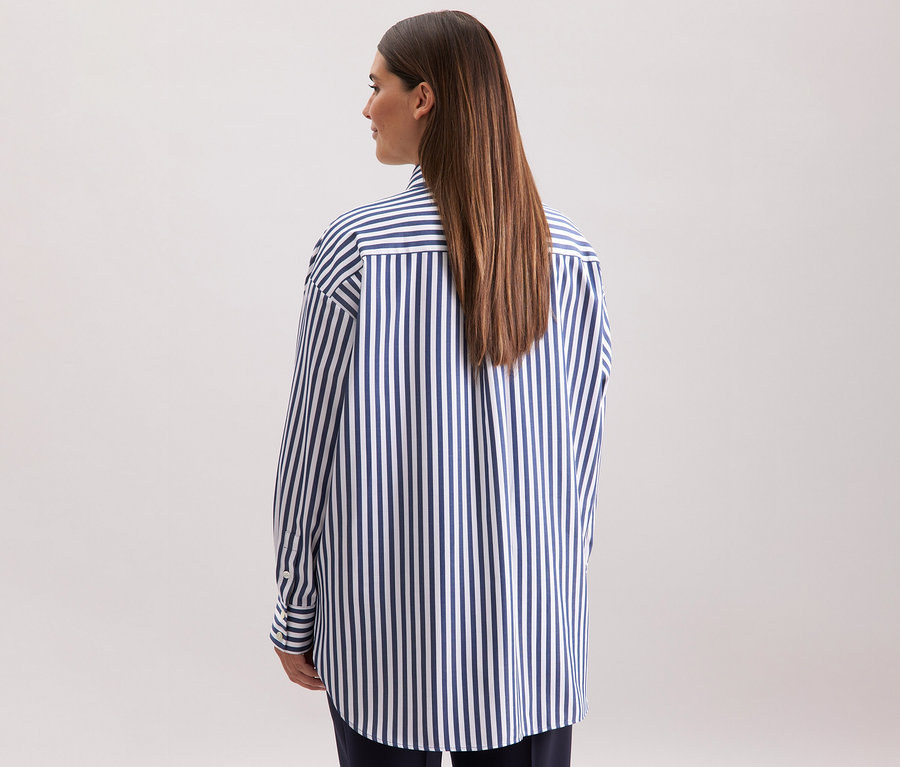 Eine Frau von hinten, die eine gestreifte Seidensticker Oversize Longbluse trägt.
