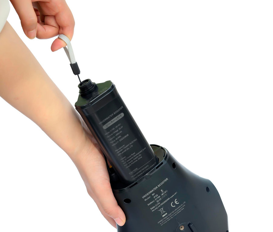 Eine Hand legt eine schwarze Spinera Underwater Powerfin and Scooter Batterie in einen schwarzen Unterwasser-Scooter.