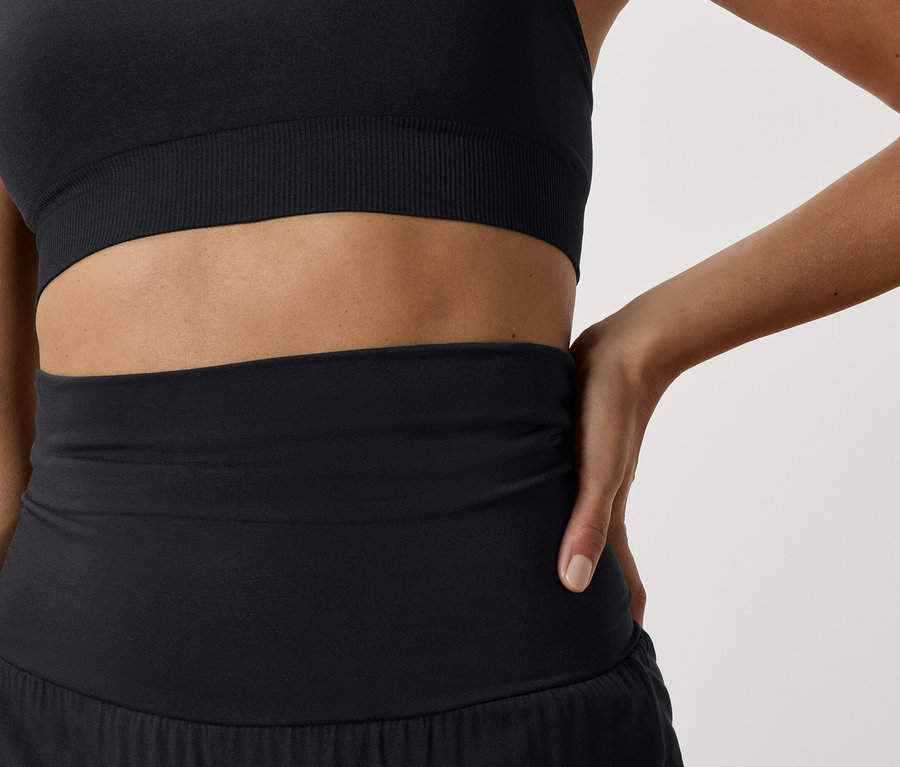 Detailaufnahme einer Frau, die einen schwarzen Sport-BH und schwarze Sportshorts trägt.