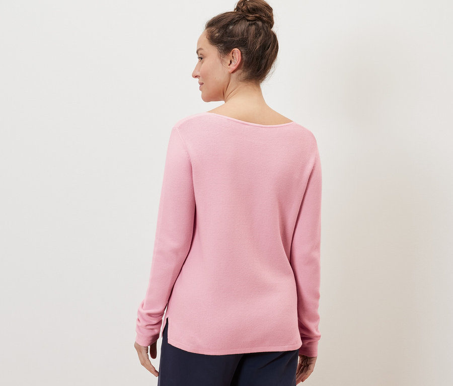 Frau trägt einen roséfarbenen Strickpullover.