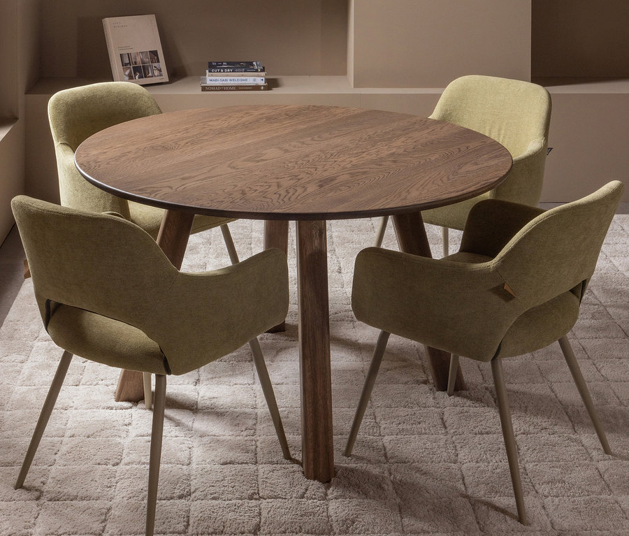 Vier Woood »Jenny« Stühle im 2er-Set in Salbei um einen runden Holztisch auf einem cremefarbenen Teppich.