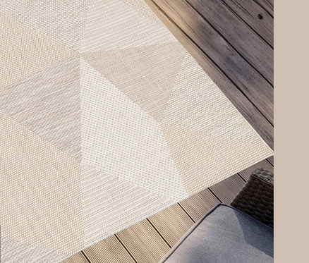 Ein Outdoor-Teppich »Sandstone Shapes« mit einem geometrischen Muster in Beige-Tönen auf einer Holzterrasse.