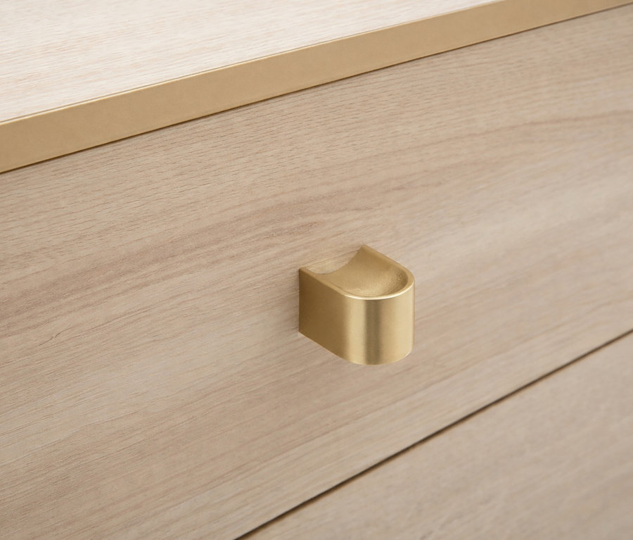 Nahaufnahme eines hellen Holzschranks mit goldenem Griff und Beschlägen.