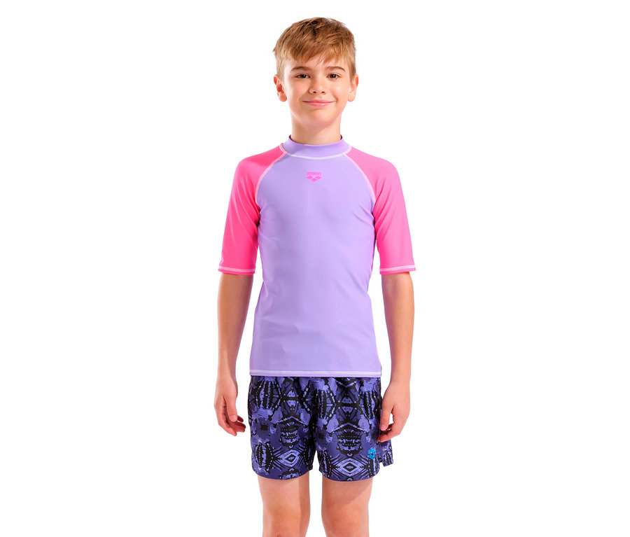 Ein junger Mann trägt ein lila T-Shirt mit pinkfarbenen Ärmeln und gemusterte Badeshorts.