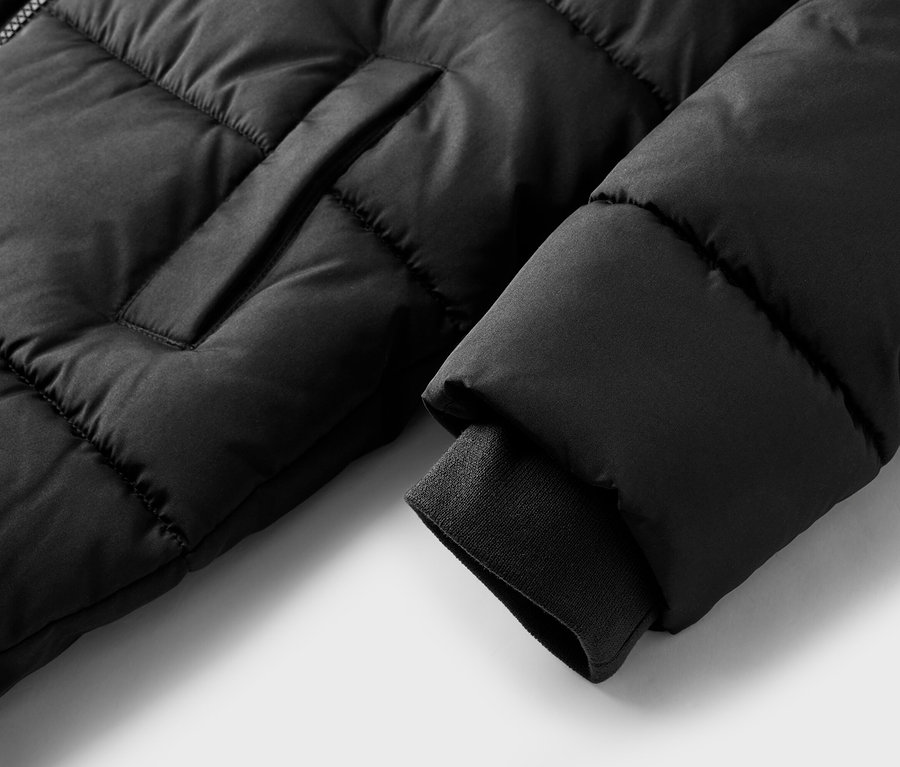 Nahaufnahme einer schwarzen Steppjacke mit geripptem Ärmelbündchen und sichtbarer Tasche.