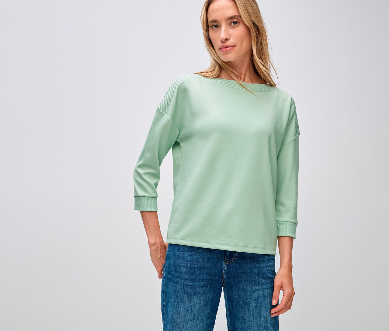 Frau trägt ein Street One, T-Shirt mit Rippdetail, salbeigrün und Jeans.
