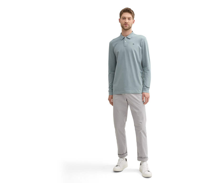 Mann in grauer Hose und mintgrünem Tom Tailor Longsleeve Piqué Poloshirt.