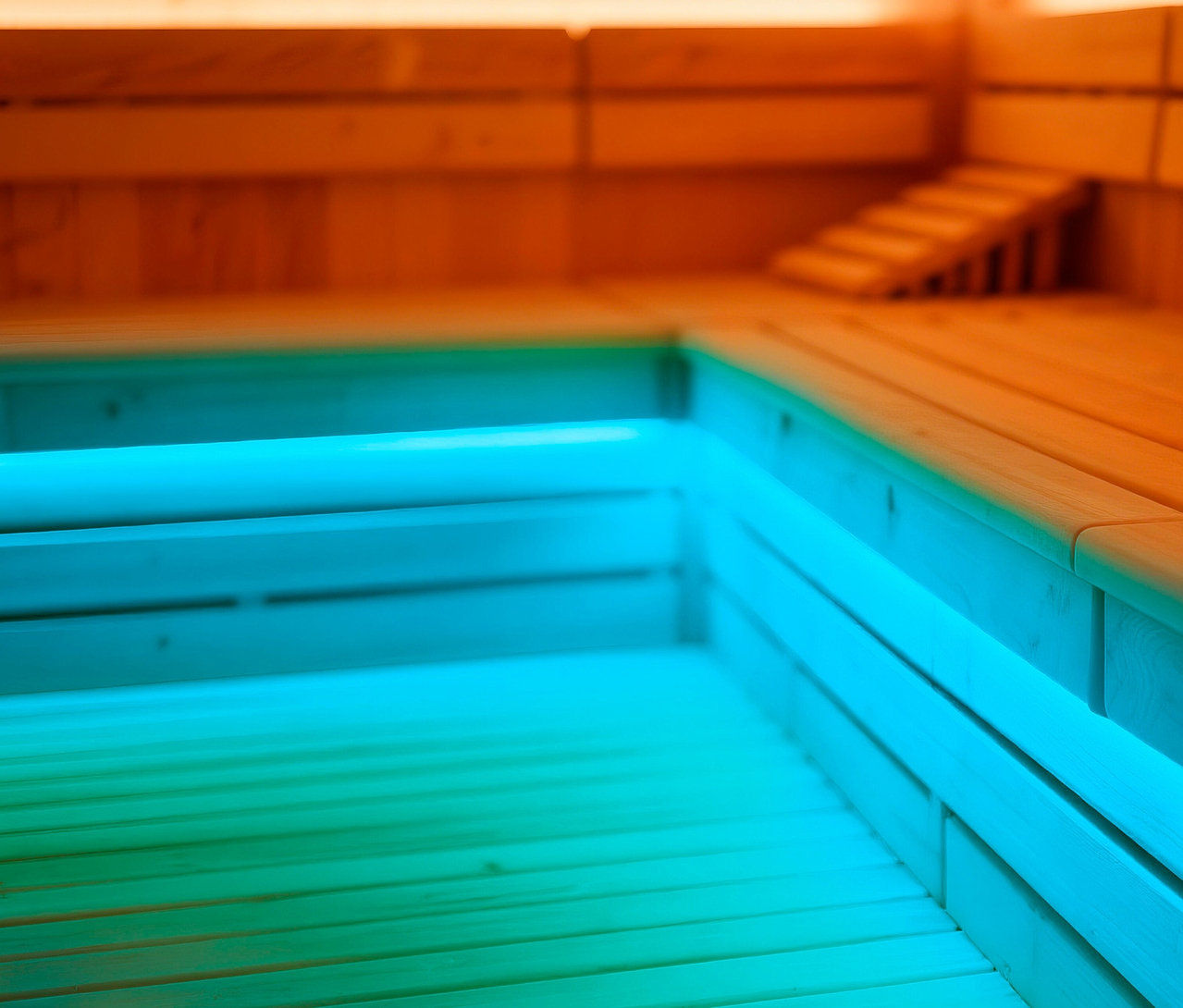 Nahaufnahme eines Saunabereichs mit blauer Beleuchtung unter den Holzbänken.