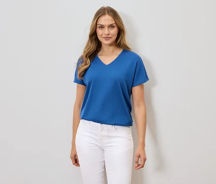 Frau trägt ein blaues T-Shirt und weiße Hosen.