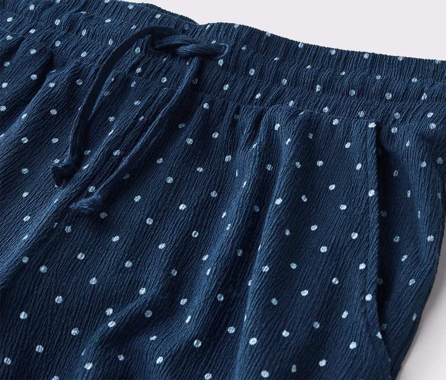 Nahaufnahme einer marineblauen Hose mit weißen Punkten, elastischem Bund und Kordelzug.