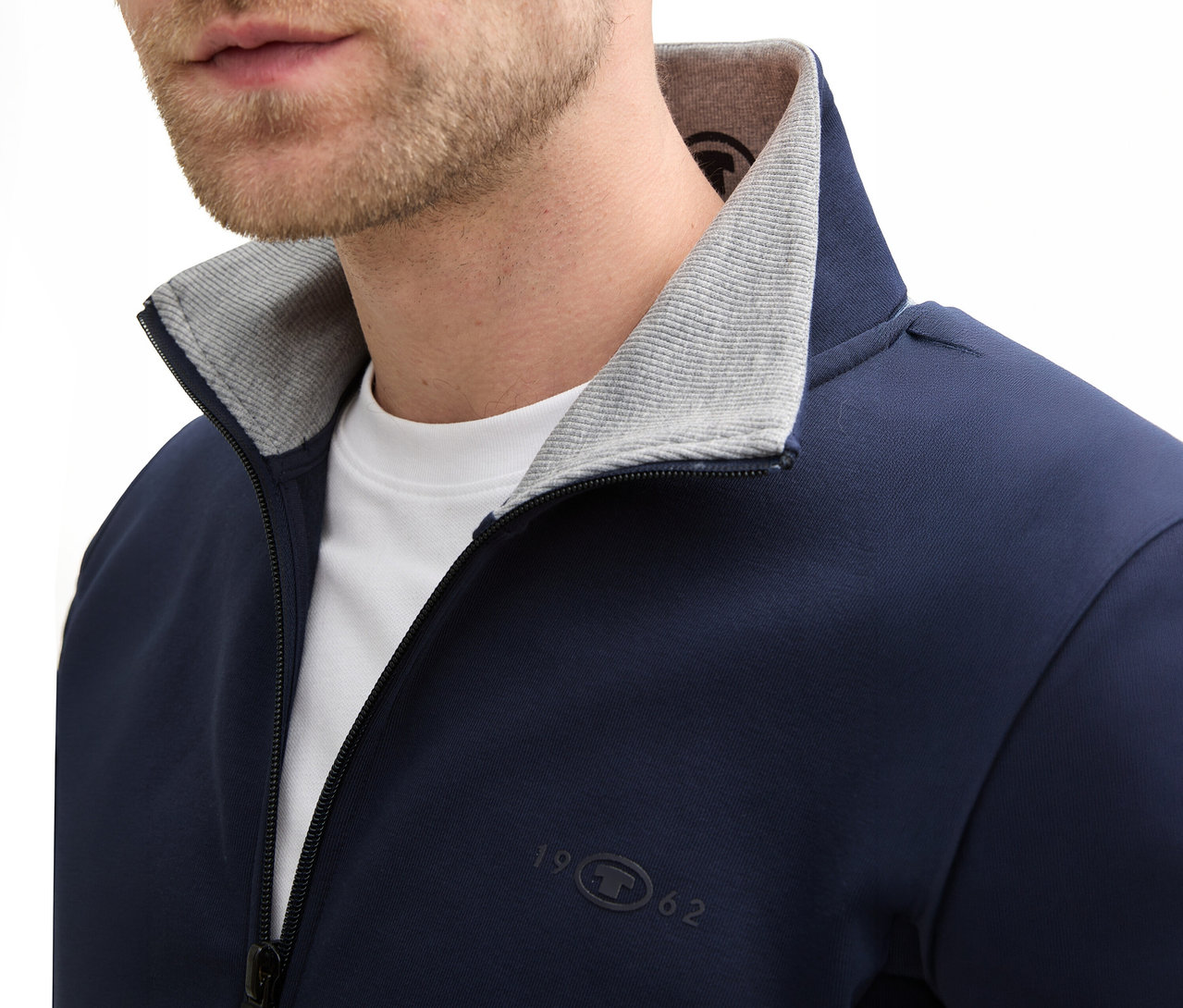 Nahaufnahme eines Mannes mit Bart, der eine marineblaue Tom Tailor Sweatjacke mit Stehkragen in Sky Captain Blue trägt.