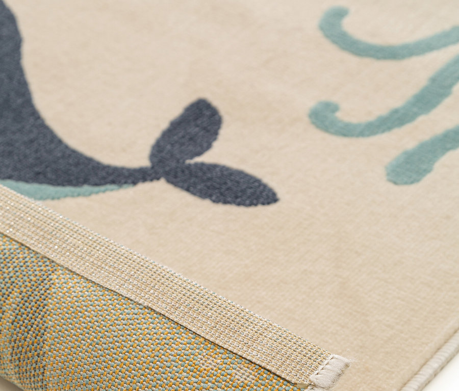 Detailansicht eines beigen Teppichs mit einem blauen Wal und türkisfarbenen Tentakeln.