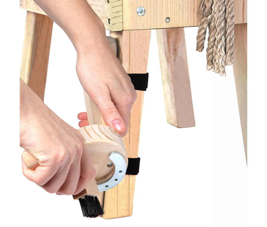 Hände benutzen ein small foot Putzhufe-Set an einem Holzpferd.