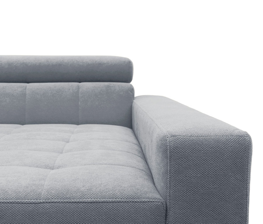 Nahaufnahme eines hellgrauen Sofas mit strukturierter Oberfläche, gesteppter Sitzfläche und Rückenlehne sowie einer Armlehne auf der rechten Seite.